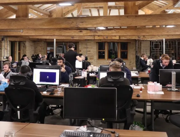 A distant shot of the Parallel Partnerships office during working hours, it is framed so that you can see the furthest wall from the camera, which means most of the office is in view.