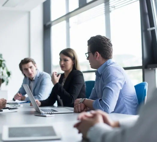 Five people sat at a long desk having meeting.