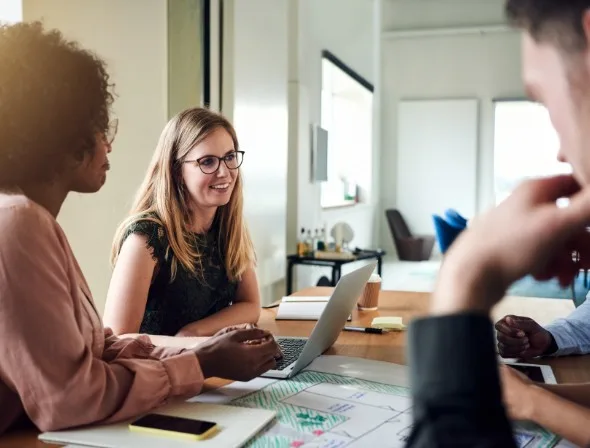 Four people sat at a desk having a meeting.