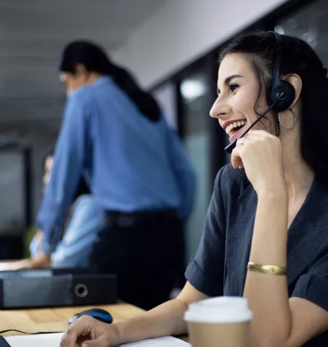 A woman who's on a telemarketing call and wearing a headset, the background is out of focus.